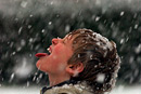 A boy let’s snow fall on his tongue