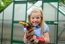 A girl with a hose smiles at a garden centre