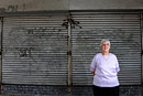 A woman outside a shop with shutters down