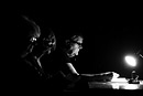 Three women study papers by lamp light, black and white image
